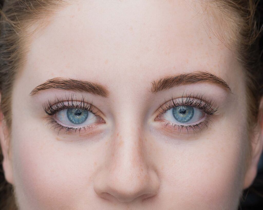 πρόσωπο γυναίκας με γαλάζια μάτια που αναδεικνύουν την ανόρθωση των φυσικών της βλεφαρίδων